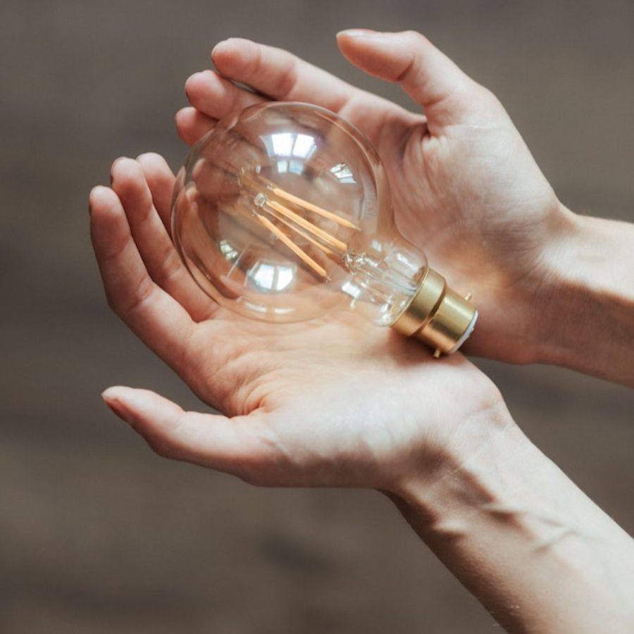 a lighted bulb sitting in female hands